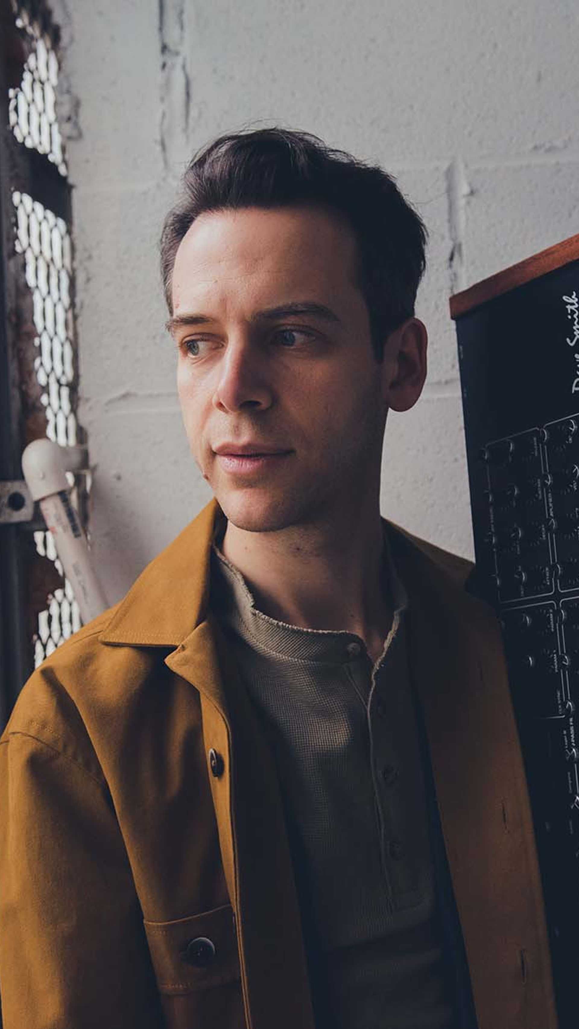 Image of keyboard player Jesse Fischer holding a keyboard in a warehouse
